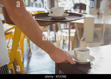 7/8 Hand der Kellner mit Kaffee auf Tisch im Cafe Stockfoto