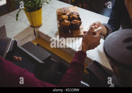 7/8-Seite der weiblichen Kunden die Zahlung für den Besitzer an der Theke im Cafe Stockfoto