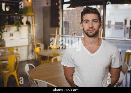 Portrait von selbstbewussten jungen Kellner steht die Tabelle im Cafe Stockfoto