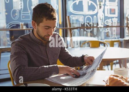 Geschäftsmann lesen Zeitung beim Sitzen auf Stuhl im Cafe Stockfoto