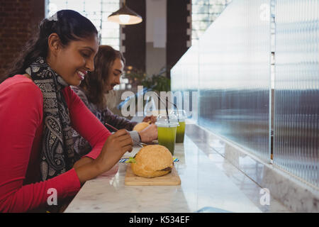 Junge Frau mit Freund Burger in an der Theke im Cafe Stockfoto