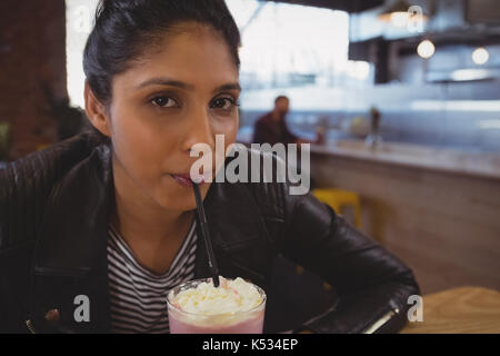 Porträt der jungen Frau trinkt Milkshakes im Cafe Stockfoto