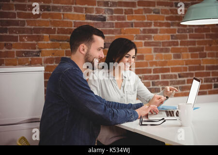 Führungskräfte diskutieren über Laptop am Schreibtisch im Büro Stockfoto