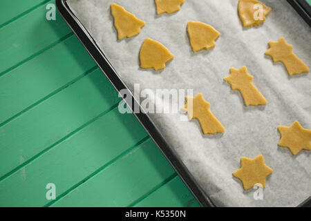 Hohe Betrachtungswinkel verschiedener Form roh Cookies in Backblech auf hölzernen Tisch Stockfoto