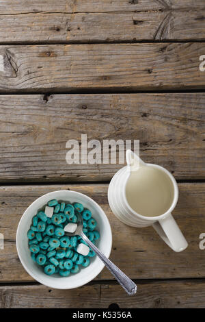 Schüssel Froot Loops und Marshmallow mit Milch Kanne auf hölzernen Tisch Stockfoto