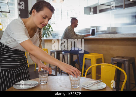 Kellnerin Gläser mit Geschäftsmann mit Laptop an der Theke im Cafe Stockfoto