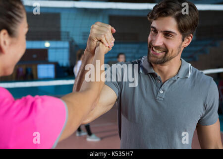 Bestimmt Volleyball Spieler die Hand mit weiblichen Mannschaftskameraden am Hof Stockfoto