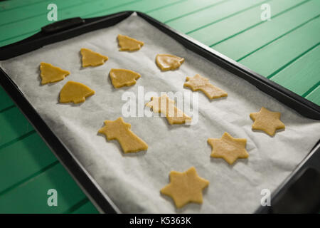 Hohe Betrachtungswinkel verschiedener Form roh Cookies in Backblech auf hölzernen Tisch Stockfoto