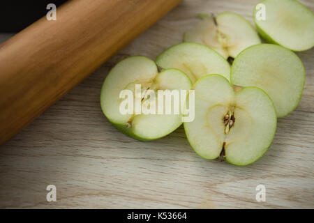 Hohe Betrachtungswinkel von Granny Smith Apfel Scheiben durch Rolling Pin auf hölzernen Tisch Stockfoto