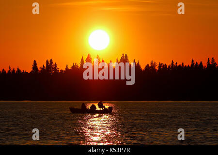 Ein Fischerboot Silhouette gegen eine leuchtende Orange Sky. Stockfoto