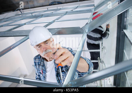 Senior Builder mit Schraubendreher auf der Baustelle Stockfoto