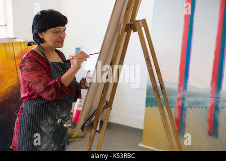 Lächelnd senior Frau Malerei beim Stehen in der Kunst Klasse Stockfoto