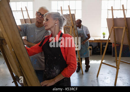 Älterer Mann an Frau Malerei suchen auf staffelei in der Kunst Stockfoto