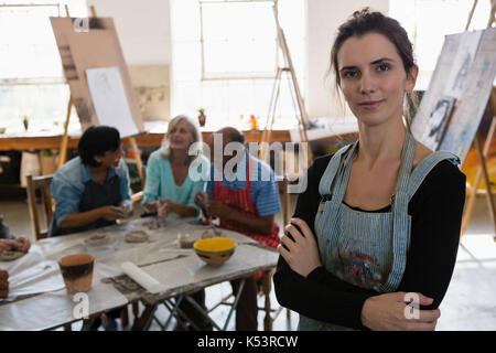 Portrait von weiblichen Ausbilder mit älteren Freunden im Hintergrund bei Tisch im Kunstunterricht Stockfoto