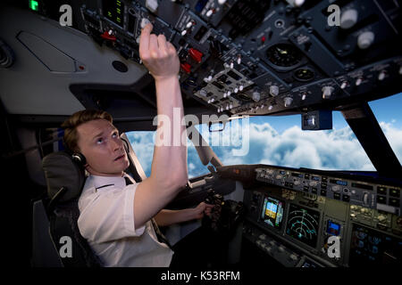 Seitenansicht des jungen männlichen pilot Switching steuert in Flugzeug Cockpit Stockfoto