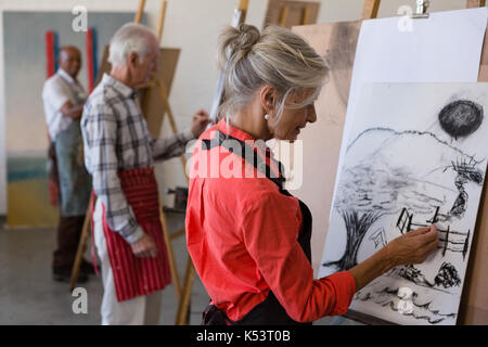 Älterer Mann und Frau Malerei auf Papier beim Stehen in der Kunst Klasse Stockfoto