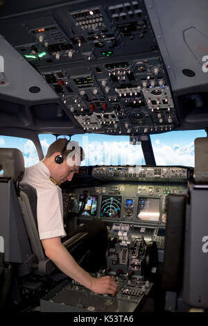 Ansicht der Rückseite des männlichen pilot Switching steuert in Flugzeug Cockpit Stockfoto