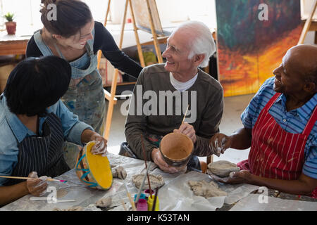 Hohe Betrachtungswinkel von lächelnden Lehrer Unterstützung von Mann und Frau Färbung Tontopf bei Tisch und in der Kunst der Klasse Stockfoto