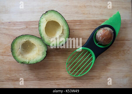 Avocado halbieren und mit drei in einem avocado Preparation Tool ausgespielt. Stockfoto