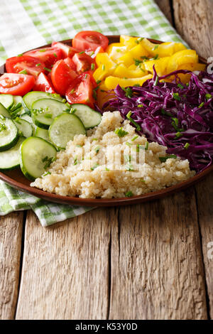 Frischer Salat aus Quinoa mit Rotkohl, Tomaten, Paprika und Gurken close-up auf einem Teller. Vertikale Stockfoto