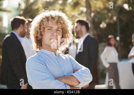 Vordere Portrait von junge Unternehmer Stehen mit verschränkten Armen außerhalb Stockfoto