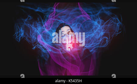 Mädchen mit einem Schädel Maske mit den Finger auf den Mund, die Stille. Der dunkle Hintergrund mit etwas Blau und Rosa Flammen aus Licht Malerei Technik Stockfoto