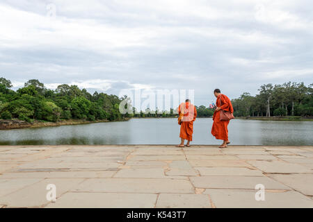 SIEM REAP, Kambodscha - 6/26/2015: Zwei Mönche zu Fuß über den Sandstein Causeway in Richtung West Gate von Angkor Wat. Stockfoto