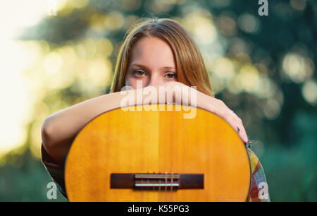 Close up Portrait eines Musikers Mädchen mit einer akustischen Gitarre aus Holz auf einem hellen Grün. Flache Freiheitsgrad. Stockfoto