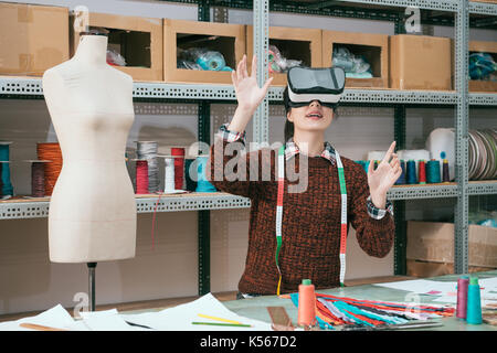 Gerne attraktive Kleidung Fabrik Arbeiterin tragen Virtuelle Realität Gerät suchen 3D Design Video- und mit Händen Verschieben von Inhalten. Stockfoto