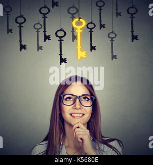 Schöne nachdenkliche Frau suchen upSmiling Frau oben Vintage goldenen Schlüssel zum Erfolg unter vielen anderen hängen. Konzept der Business aspirati Stockfoto