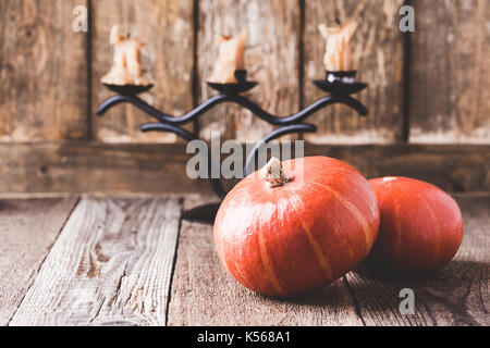 Herbst gemütlich zu Hause Dekorationen. Stilleben mit Kürbis und Kerzen auf Holz- rustikalen Hintergrund Stockfoto