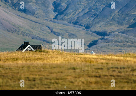 Bergige Landschaft mit einem ländlichen Haus sichtbar über dem Feld im Vordergrund. Stockfoto