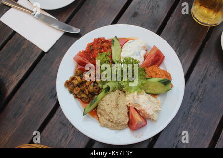 Türkische Sharing Platter mit Dips einschließlich Hummus, Paprika, Karotte, Tomate und Tzatziki serviert mit Grüns. Stockfoto