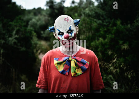 Nahaufnahme der Ein unheimlich bösen Clown tragen ein schmutziges rot Kostüm in den Wäldern Stockfoto