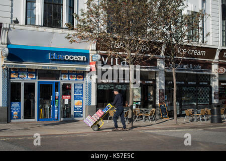 Ein Delivery man Spaziergänge entlang der South Street in Worthing, West Sussex, England, UK. Stockfoto