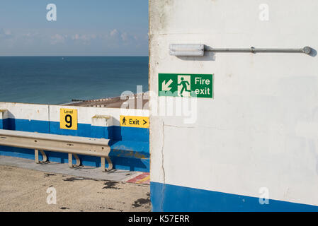 Ein Notausgang Schild oben auf dem Parkplatz mit Blick auf das Meer. Stockfoto