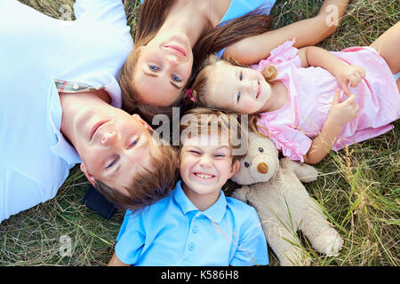 Glückliche Familie liegen auf Gras Blick von oben. Stockfoto
