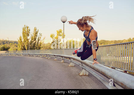 Ein Mädchen runner springt über ein Geländer auf einer Brücke in der Stadt. Stockfoto