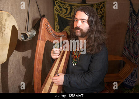 Largs, Schottland, Großbritannien. September 2017. David Cambert ein Clarsach Harpharpist in der Schlacht von Largs (2. Oktober 1263) eine Re-enactment Veranstaltung von den Schwertern von Dalriada, 13. Jahrhundert, lebendige Geschichte Gruppe. Es war ein unentschlossenes Engagement zwischen den Königreichen von Norwegen und Schottland, am Firth of Clyde in der Nähe von Largs, Schottland. Der Konflikt war Teil der norwegischen Expedition gegen Schottland im Jahr 1263, in der Haakon Haakonarson, König von Norwegen versuchte, die norwegische Souveränität über die westliche Küste Schottlands wieder zu behaupten. Stockfoto