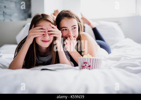 Jugend Mädchen essen Popcorn und beobachten Horrorfilm im Fernsehen zu Hause Stockfoto