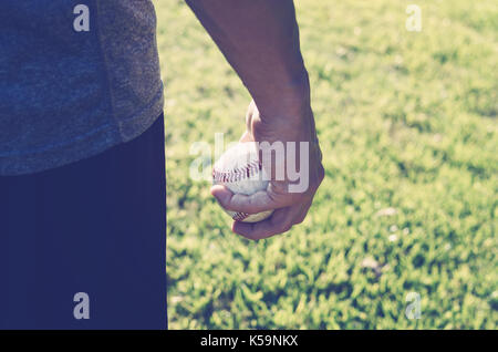 Baseball Spieler mit Ball in Hand während der natürlichen Sonnenuntergang, großartig für amerikanischen Sport Grafik. Stockfoto