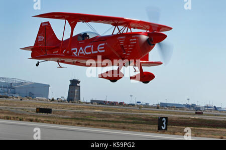 Sean D. Tucker flys Oracle Doppeldecker, wie er weg nimmt bfm Oakland International Airport mit einem Blauen Engel in 2009 zu fliegen. Stockfoto