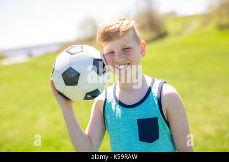 Junge holding Fuß ball im Park. Stockfoto