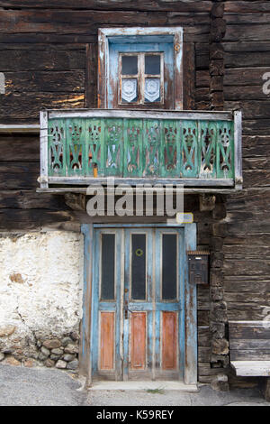 Alten rustikalen hölzernen Tür und Fenster in einem Holzhaus mit einem kleinen Balkon und einer Bank ausserhalb Stockfoto