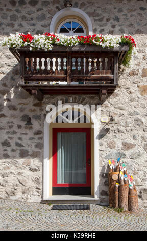 Bunte Blumen in einem Fenster Feld über eine gewölbte Glastür in einer Natursteinmauer mit Gardinen Stockfoto