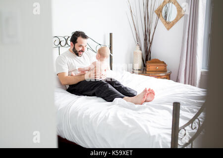 Junge gerne Vater spielen mit babyon Bed Stockfoto