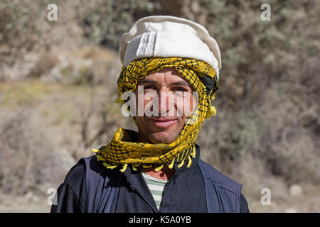 Close up Portrait von lächelnden Pamiri/Badakhshani Mann mit traditionellen Kopfbedeckungen, Provinz Gorno-Badakhshan, Tadschikistan Stockfoto