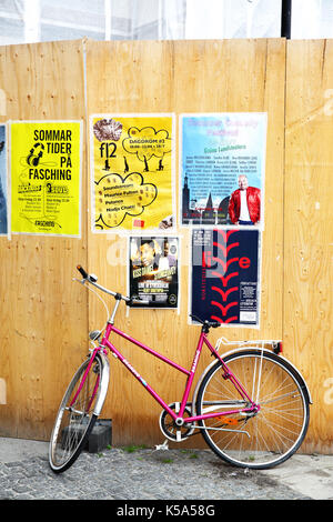 Stockholm, Schweden - 25. Juli 2017: Mit dem Fahrrad in der Nähe von Zaun mit ad Poster in Stockholm. Stockfoto