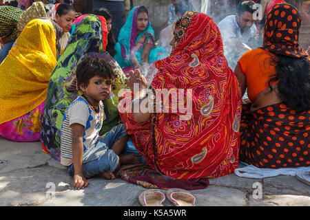 KATHMANDU, Nepal - 9/26/2015: Ein Junge sitzt mit hinduistischen Frauen in traditionellen Sari am Durbar Square in Kathmandu, Nepal. Stockfoto