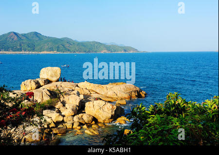 Ein Blick auf die Bäume und Blumen in Nha Trang Bucht mit Pearl Island Resort im Hintergrund. Stockfoto